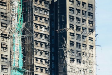 Skyscraper damaged by fire with scaffolding and netting